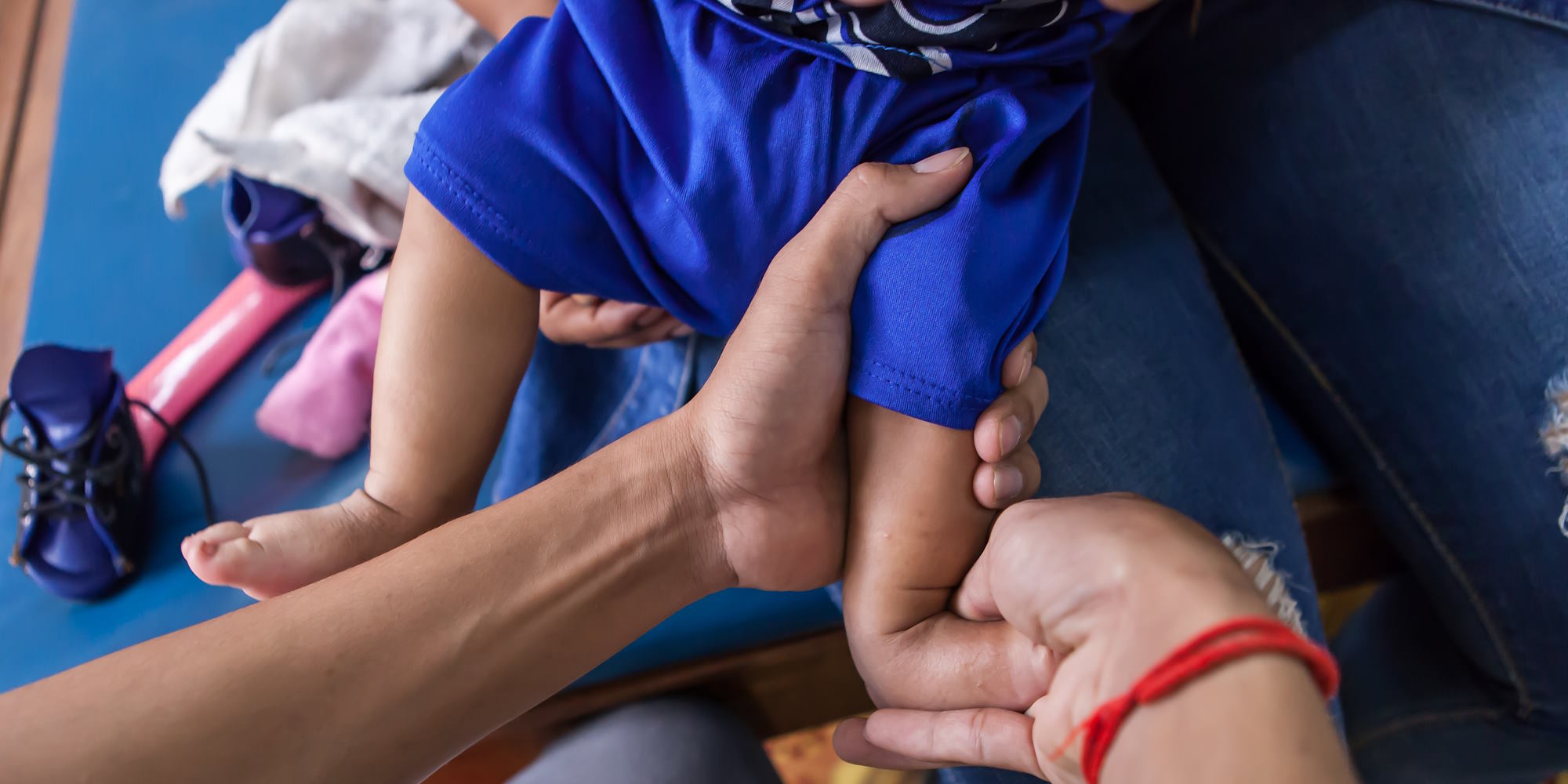 Die Hände einer Physiotherapeutin halten Babyfüße