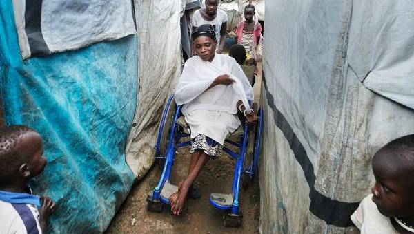 Lina, die im Rollstuhl sitzt, braucht im Flüchtlingscamp Unterstützung, um durch die engen, unebenen Gänge zu kommen.