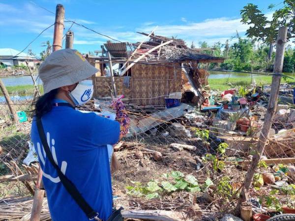 Projektleiterin von HI, Melanie Ruiz, steht nach einem Taifun vor einem zerstörten Zuhause.