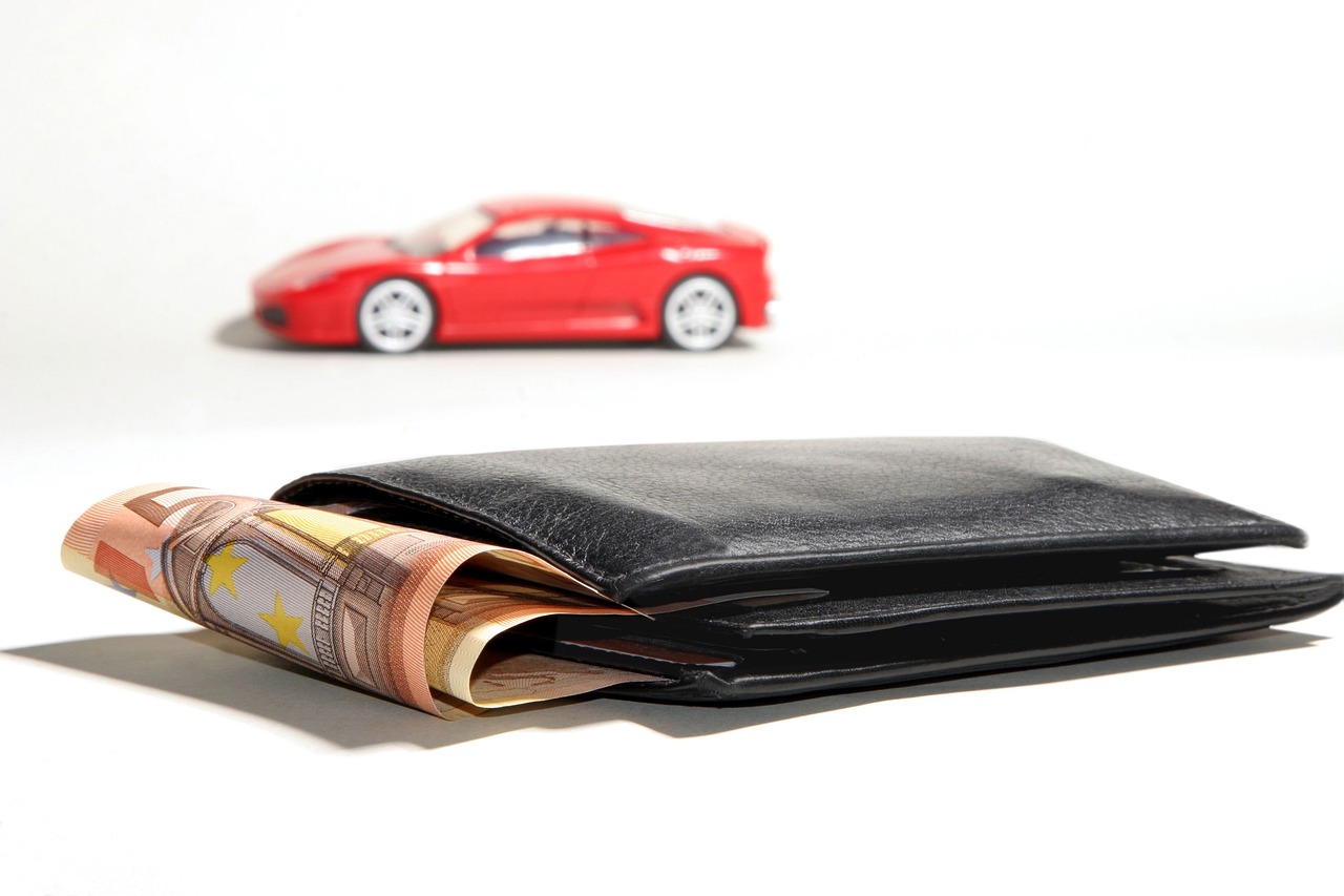 Geld im Portemonnaie, im Hintergrund ein rotes Auto