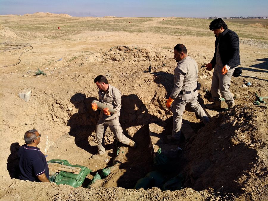 4 männer platzieren eine Bombe in einem zuvor ausgehobenen Loch.