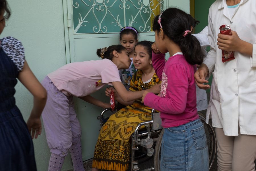 Ikram mit ihren Klassenkameraden. Eine Mitschülerin gibt ihr einen Kuss auf die Wange. Alle wirken glücklich.