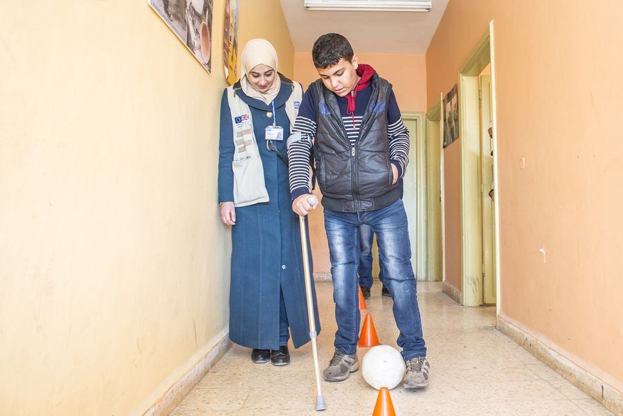 Zu sehen ist Qusay ein vierzehnjähriger Junge, der beide Beine bei einem Angriff auf sein Heimatdorf in Syrien verlor. Auf dem Bild sieht man, wie er unter Anleitung einer Physiotherapeutin auf eine Krücke gestützt 