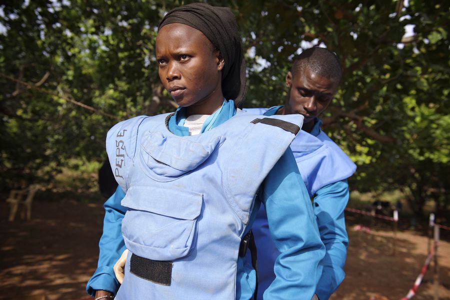 Zu sehen ist Fatou mit schwarzem Kopfband und blauer Entminungsschutzuniform. Sie bereitet sich auf ihren Einsatz vor.