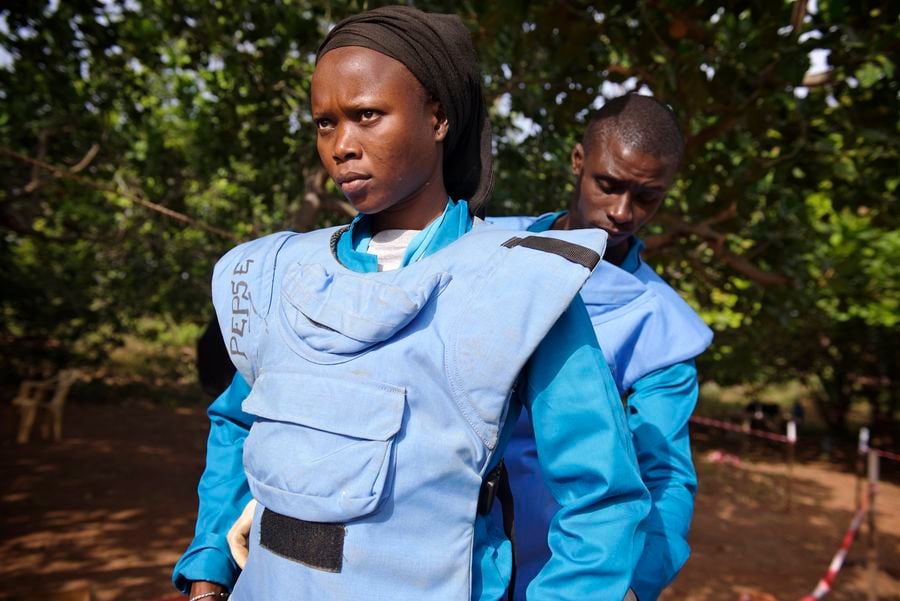 Zu sehen ist Fatou mit schwarzem Kopfband und blauer Entminungsschutzuniform. Sie bereitet sich auf ihren Einsatz vor.