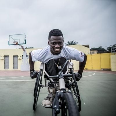 Rennrollstuhl-paralympics-kongo John Mwegani in seinem neuen Rollstuhl auf einem Sportplatz