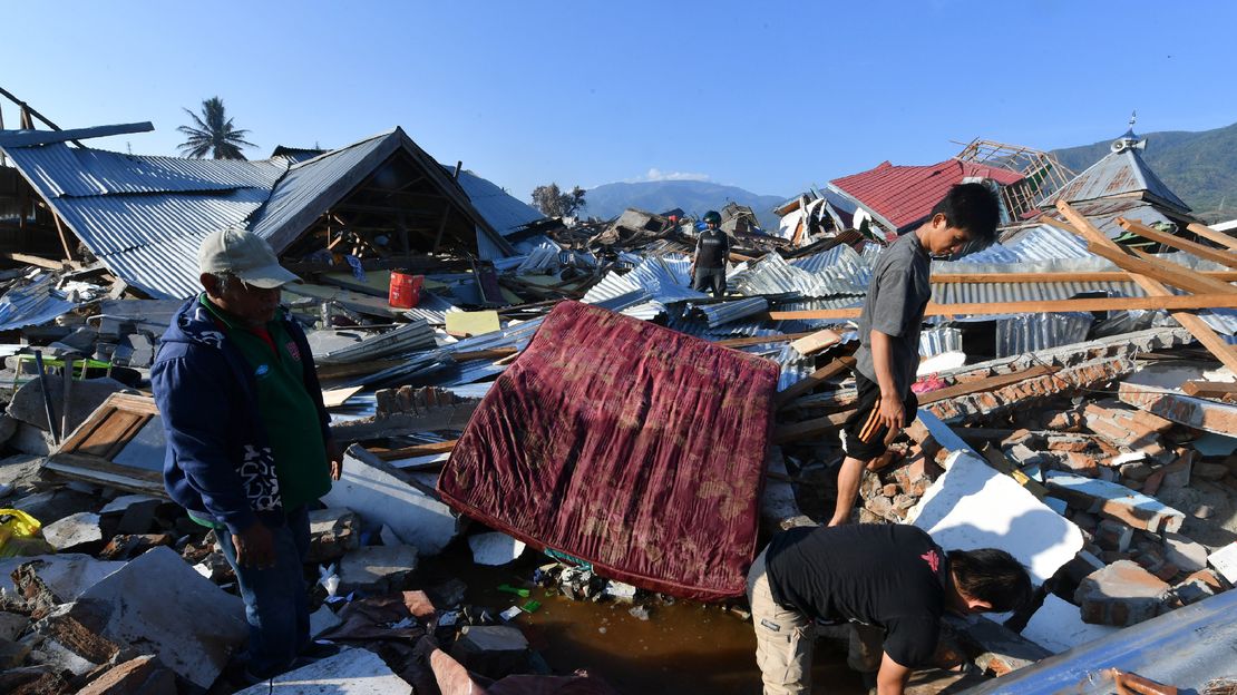 Indonesische Männer suchen nach dem Erdbeben und Tsunami in ihrem beschädigten Haus im Balaroa-Dorf in Palu ein Familienmitglied.