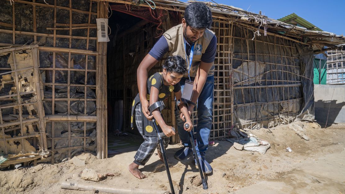 Shumira, 10 Jahre, versucht im Teknaf Camp mithilfe ihres Therapeuten das Laufen auf Krücken. Sie ist vor ihrer Unterkunft zu sehen.