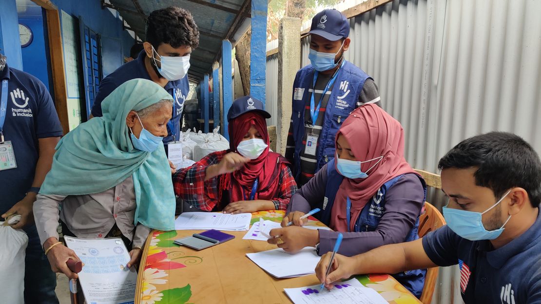Mitarbeiter von HI verteilen Kits an eine ältere Dame, die in dem Rohingya Flüchtlingslager in Bangladesch lebt.