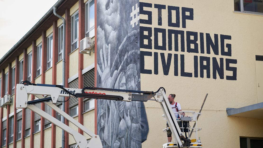 Vogelperspektive auf das haushohe Graffiti gegen die Bombardierung der Zivilbevölkerung im Münchner Werksviertel