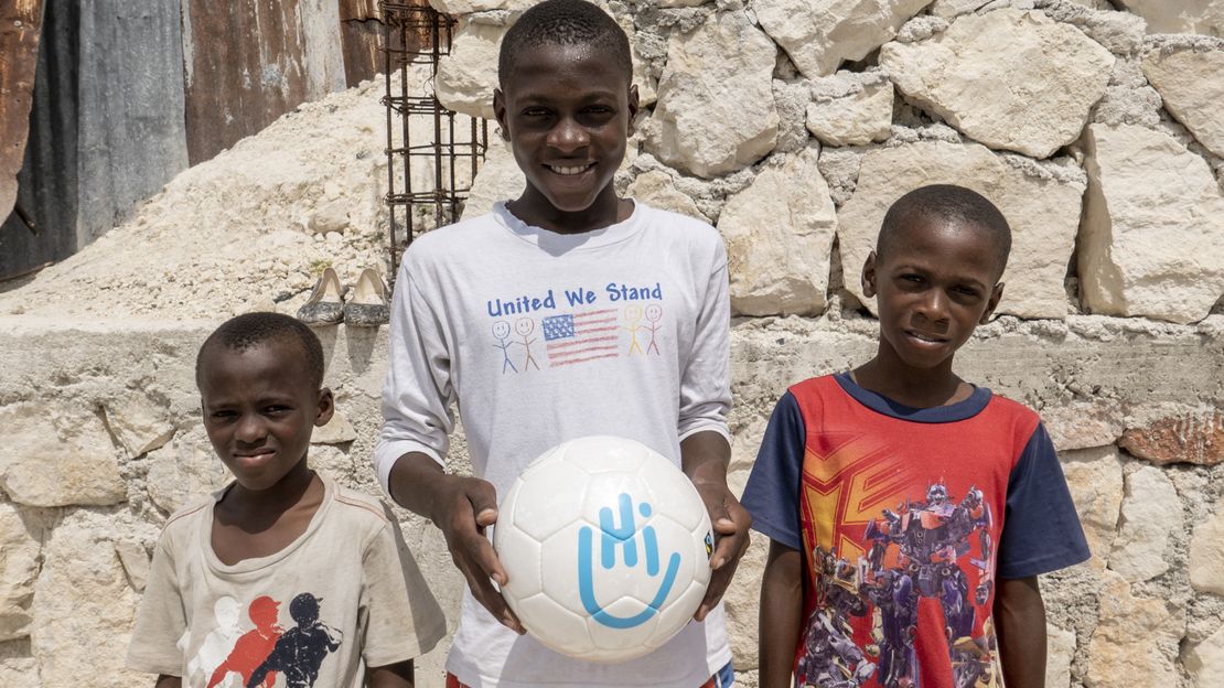 Moise mit seinen Brüdern hält einen Fußball in der Hand.