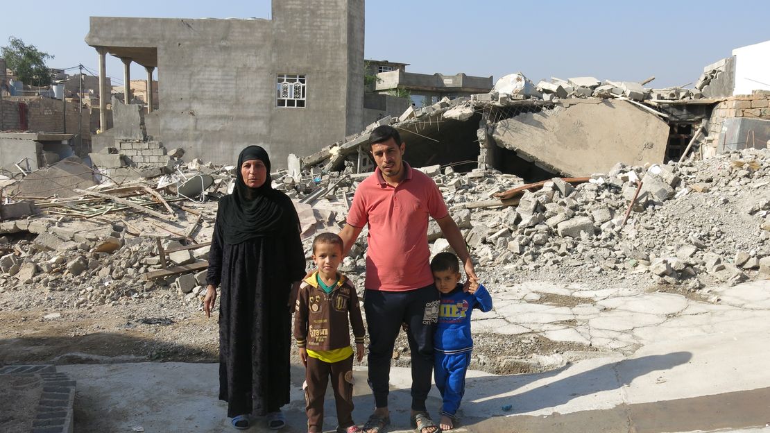 Familie mit zwei Söhnen vor den Überresten ihres Hauses im Irak, das durch Bombardierungen auf Wohngebiete zerstört wurde.