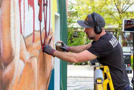 Künstler besprüht die Wand mit einem Graffiti in Augsburg.