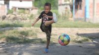Der kleine Junge Prabin kickt mit seiner Beinprothese einen Fußball.