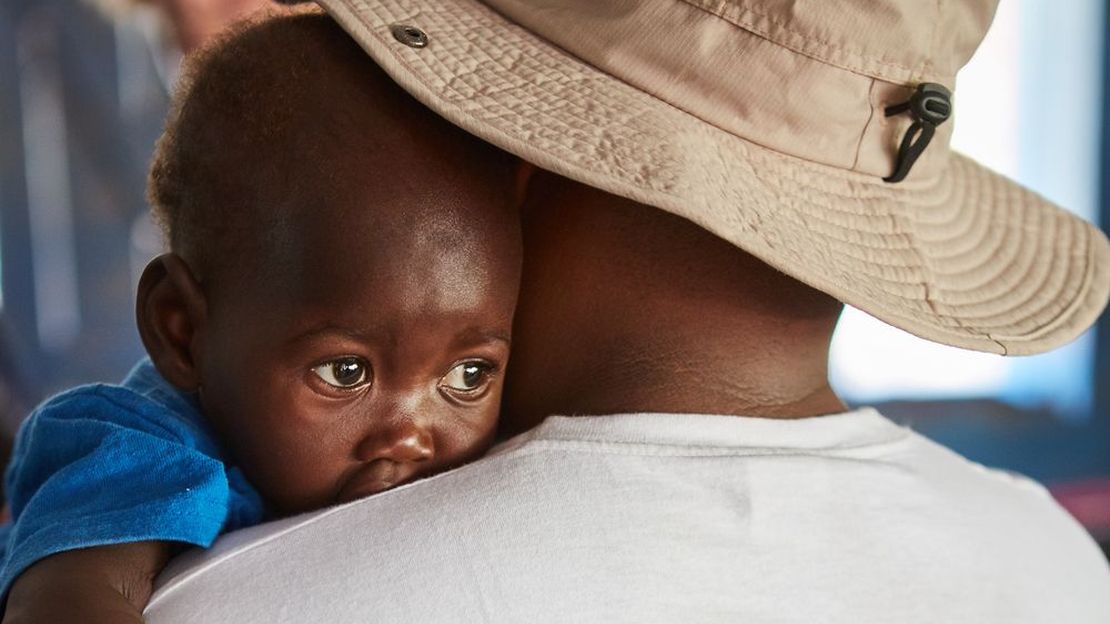 Vertrauensvoll kuschelt sich die 2-jährige Shanon Oyiela nach der Behandlung an Therapeut Simon Njenga