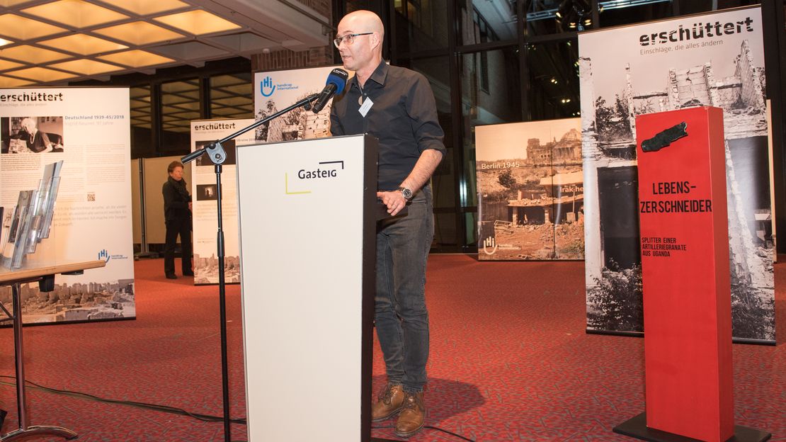 Autor und Fotojournalist bei der Eröffnungsrede seiner Ausstellung im Gasteig München am Rednerpult vor den Ausstellungs-Roll-Ups