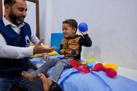 Eine junge Frau mit Prothese läuft über einen Hindernisparcour. Ein Physiotherapeut von HI unterstützt sie dabei.