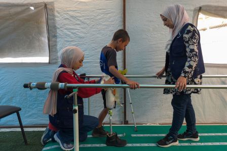Eine HI-Expertin erklärt einer Gruppe Frauen in einem Flüchtlingscamp, woran Blindgänger zu erkennen sind. Zur Veranschaulichung hat sie ein Plakat dabei.