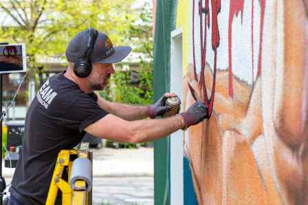Der Künstler AKUT besprüht die Hauswand in Augsburg