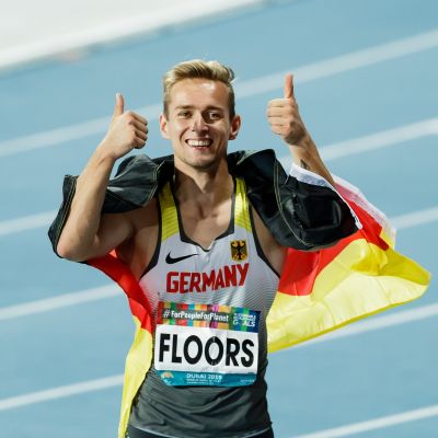 Johannes Floors hat eine Deutschlandflagge um die Schultern und streckt die Daumen raus.