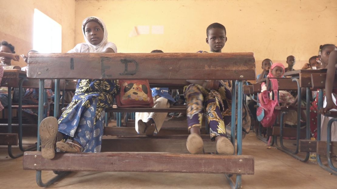 Zwei Mädchen mit einer Behinderung sitzen auf der Schulbank.