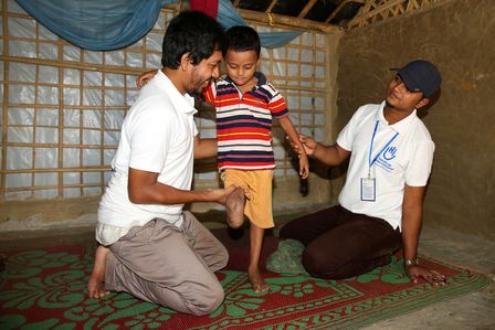 Dem 5-jährigen Anowar aus Myanmar fehlt ein Bein. Zwei HI-Therapeuthen helfen ihm bei der Therapie.