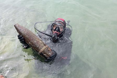 Taucher holt eine Bombe aus dem Wasser.