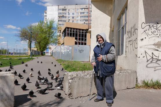 Eine 86 Jahre alte Frau mit Krücke vor einem Wohnkomplex.
