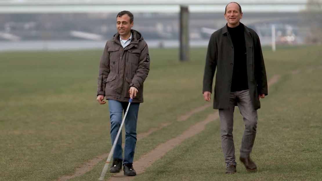 Mohamed Jolo und HI-MitarbeiterWolfram Buttschardt gehen nebeneinander spazieren. 