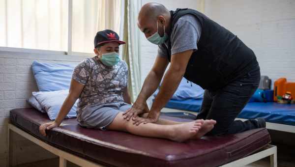 Syrischer Junge macht Übungen mit seinem Physiotherapeuten.
