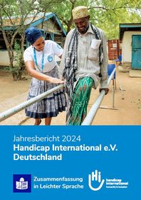 Cover Jahresbericht. Eine HI-Mitarbeiterin hilft einem Mann beim Laufen üben zwischen Stangen.