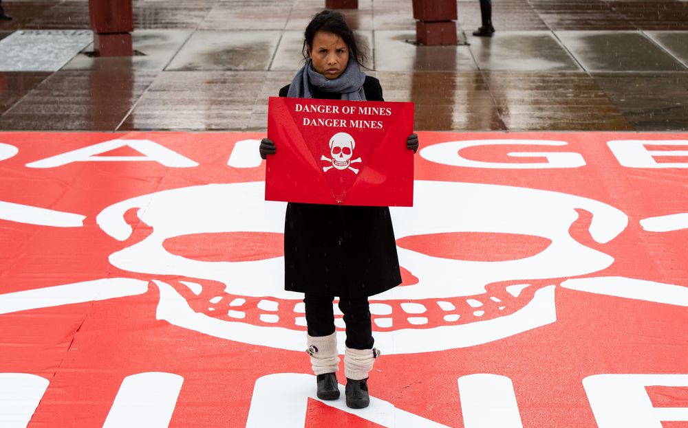 Gnep Smeoun wurde Opfer einer Landmine und hält ein Schild mit der Aufschrift "Danger Mines"