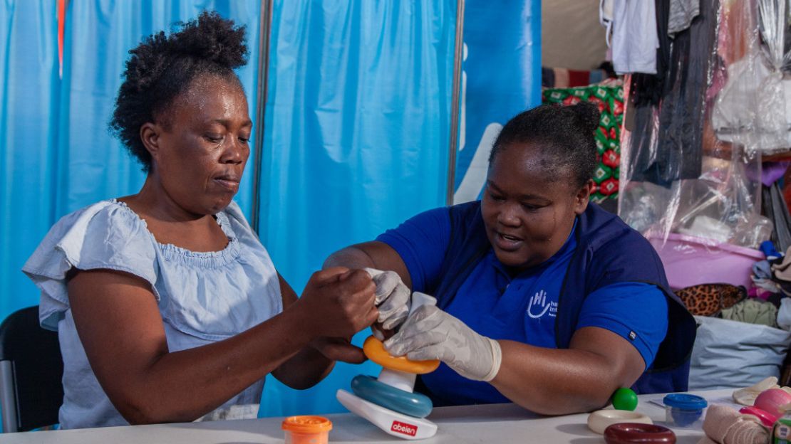 Ergotherapeutin Gaëlle unterstützt Eugénie in einem provisorischen Flüchtlingslager in Haiti bei Handübungen zur Rehabilitation.
