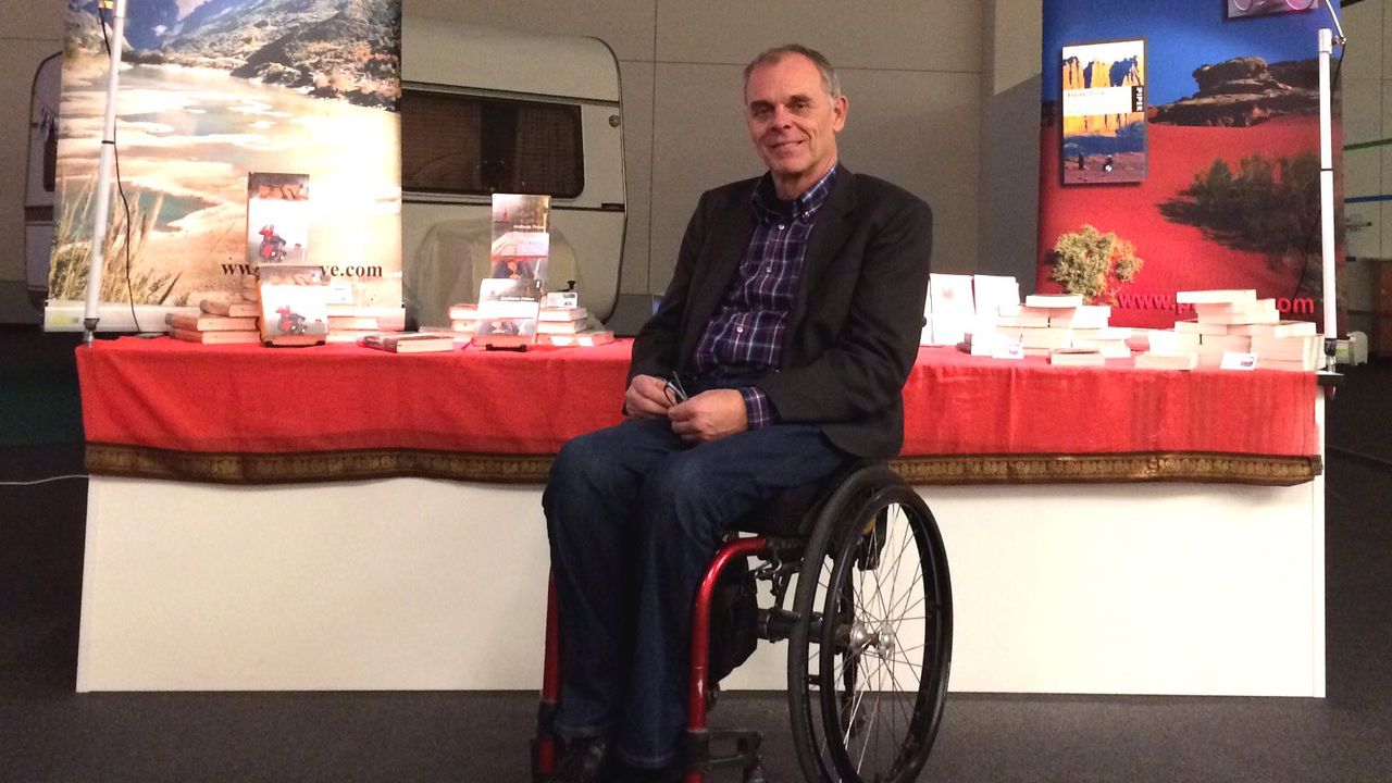 Andreas Pröve sitzt im Rollstuhl vor seinem Präsentationsstand.