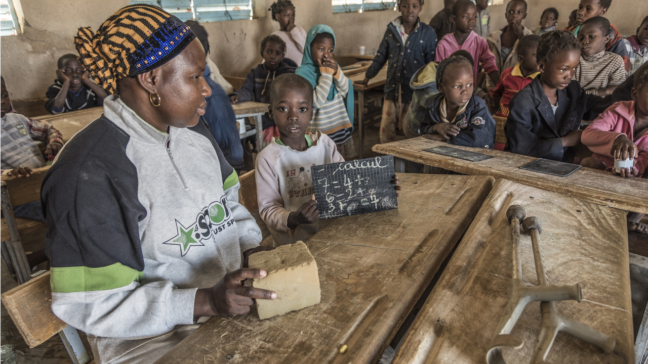 Samadou präsentiert stolz seine Rechentafel, neben ihm die pädagogischen Gastlehrerkraft, die ihn unterstützt