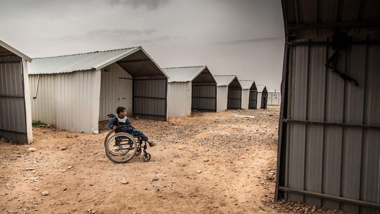 Ein Kind im Rollstuhl sitzt einsam in einem Flüchtlingscamp