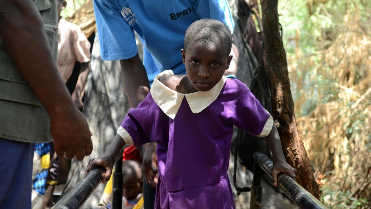 Halima trainiert an den Barren vor ihrem Haus. Ein Helfer von Handicap International unterstützt sie dabei.