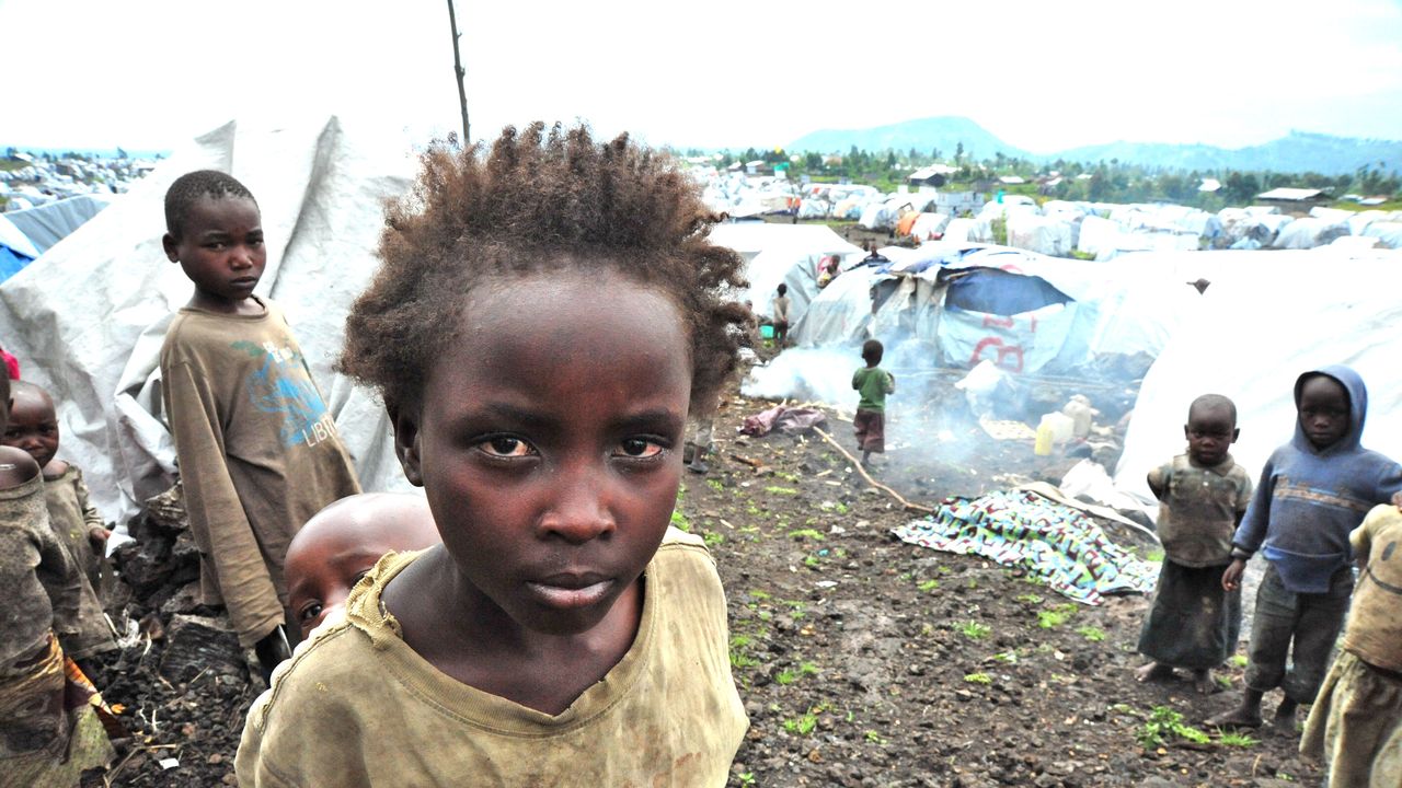 Zu sehen sind Kinder im Flüchtlingslager Mugunga 3 nahe Goma, Kongo. EIn Mädchen blickt intensiv in die Kamera. Im Hintergrund sind hunderte Zelte zu sehen.