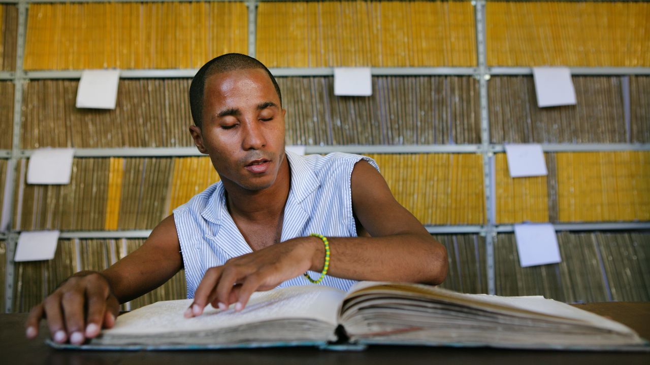 Ein junger Mann liest mit den Finger Braille-Schrift