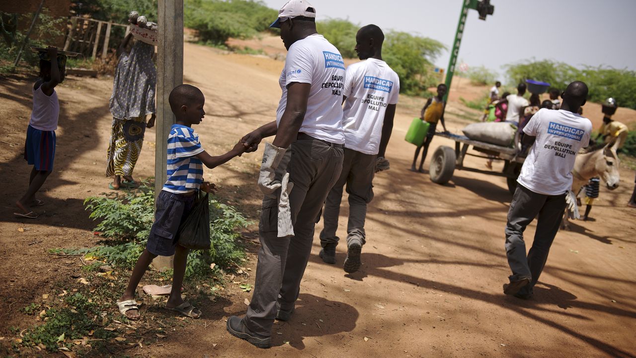 Ein Kind gibt einem unserer Mitarbeiter in Mali die Hand.
