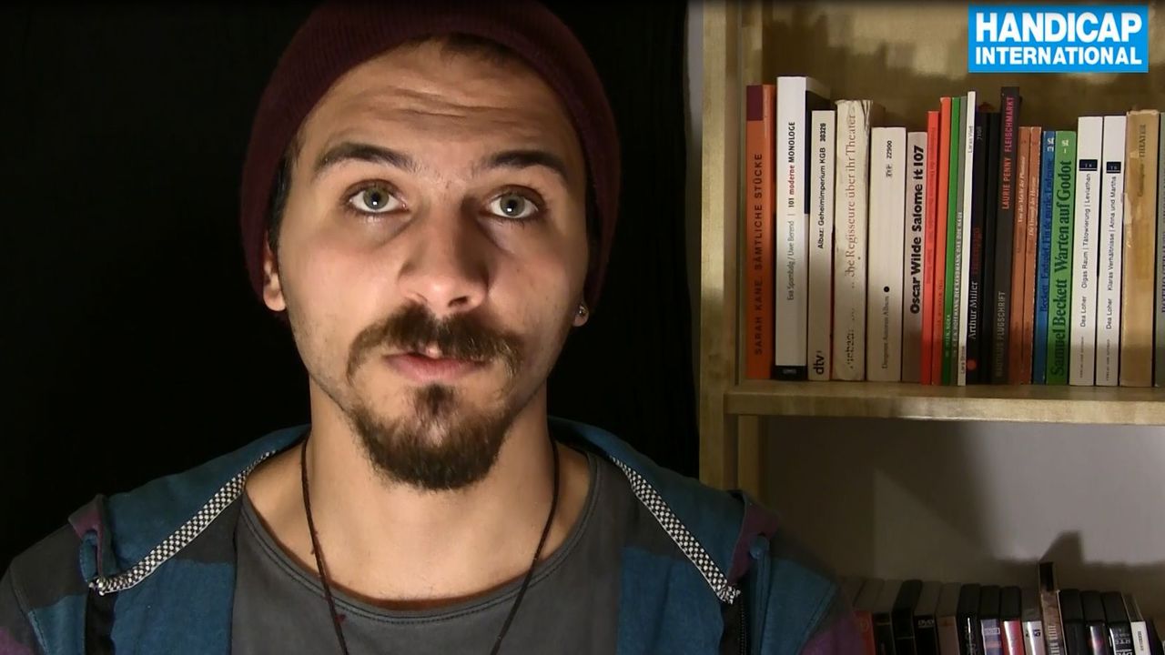 Sami schaut in die Kamera, im Hintergrund ist ein Bücherregal
