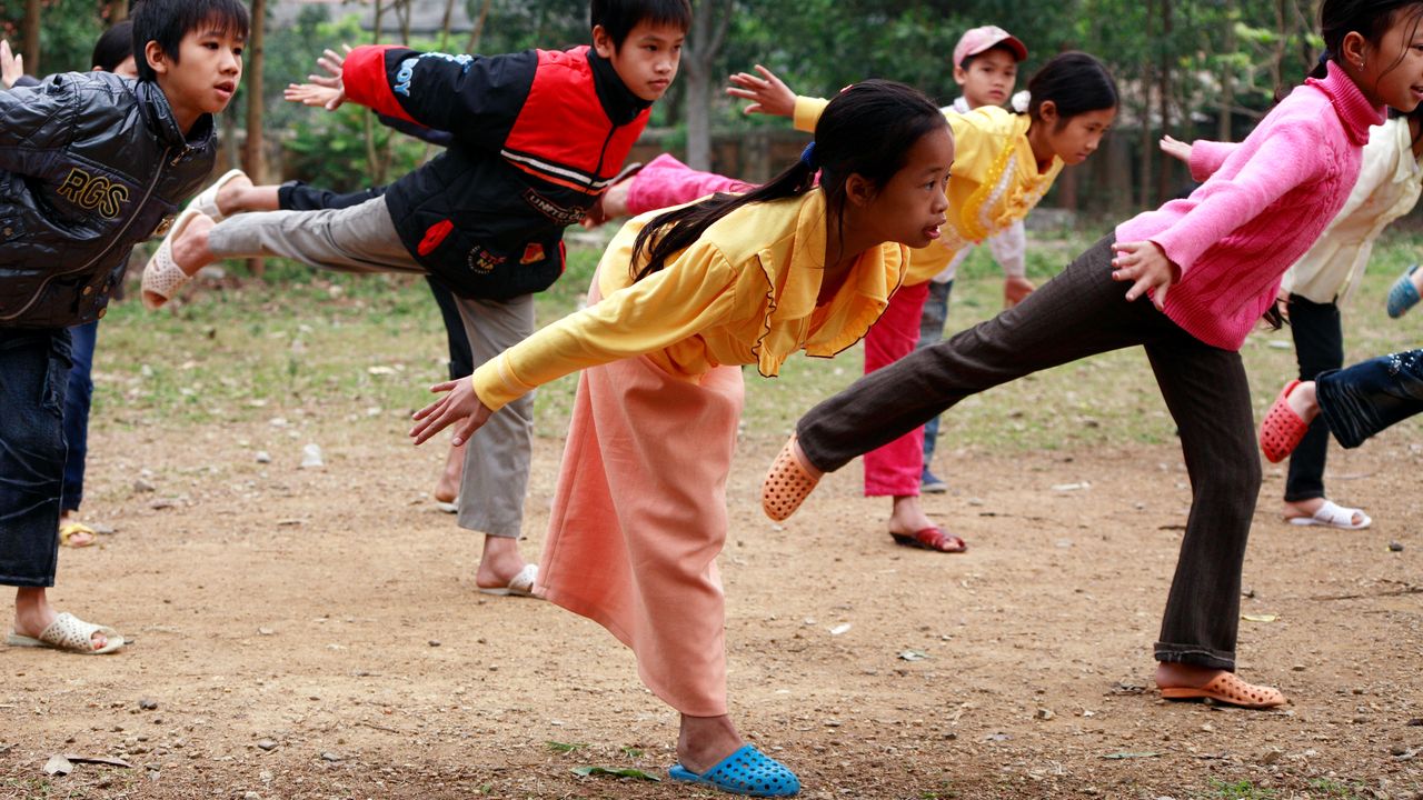 Morgensport an einer inklusiven Schule in Vietnam. Ein junges Mädchen hat nur ein Bein.