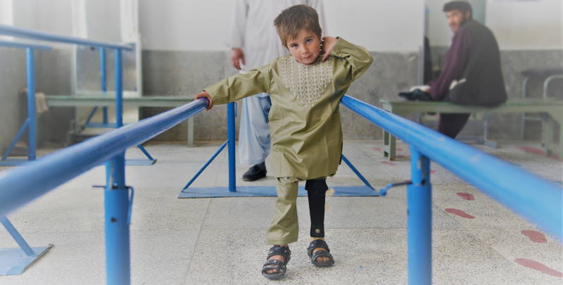 Sayed, ein kleiner Junge aus Afghanistan, übt das Laufen mit seiner neuen Beinprothese.