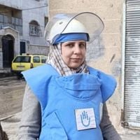 Portrait einer Frau mit Entminungskleidung (Helm und Schutzanzug).