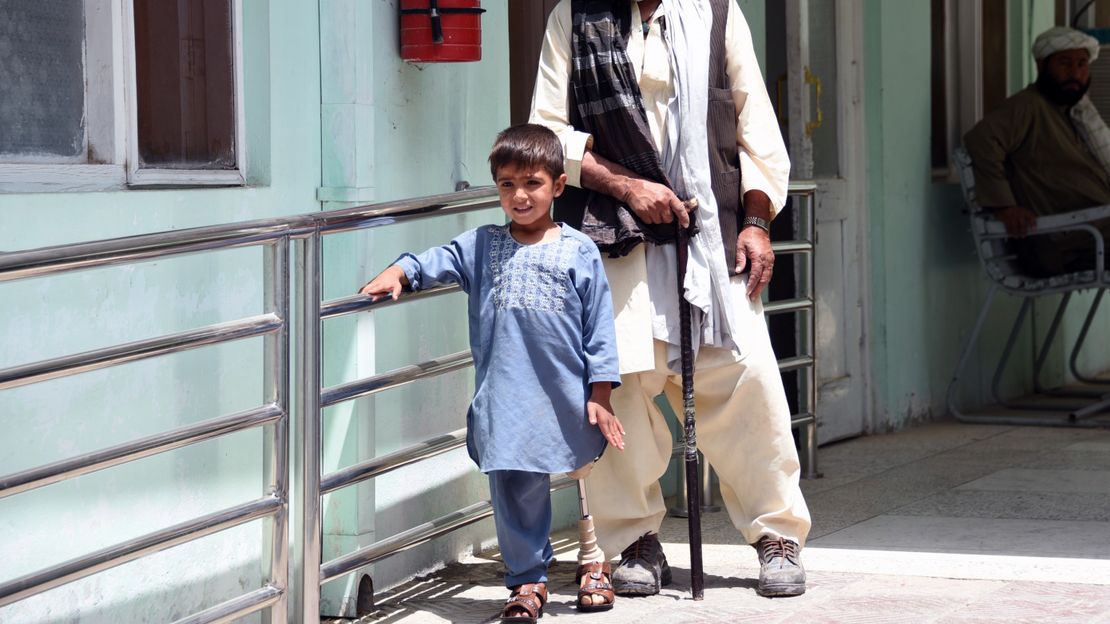 Der kleine Sanaullah aus Afghanistan an der Hand seines Therapeuten. Er trägt eine Beinprothese.