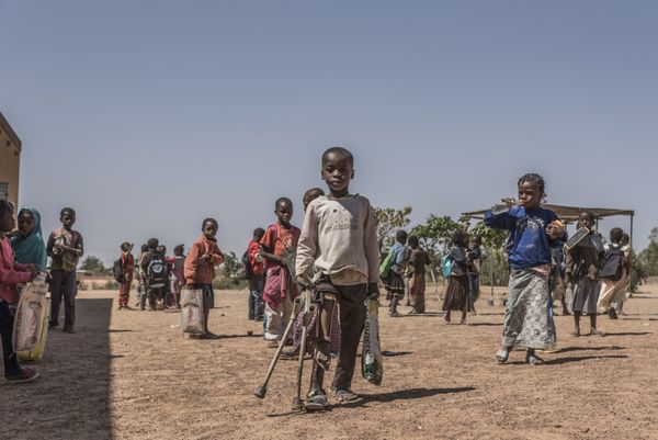 Der kleine Samadou mit seiner Prothese auf dem Schulhof in Burkina Faso inmitten anderer Schüler
