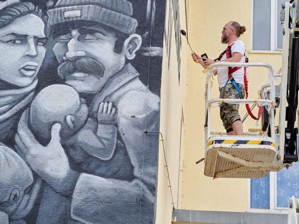 Graffiti-Künstler LANDO bei der Arbeit zum haushohen Kunstwerk im Münchner Werksviertel auf einer Hebebühne.