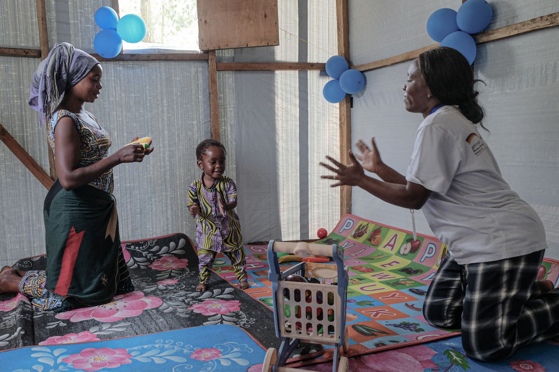 Sitzung Stimulationstherapie in der Demokratischen Republik Kongo. Mutter und Physiotherapeutin spielen mit Kind