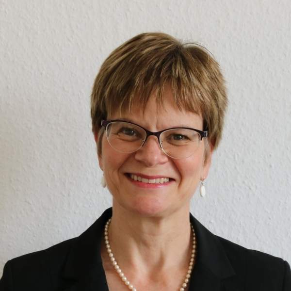 Eine Frau mit kurzen bloden Haaren lacht eine andere Frau mit grauen Haaren an, die man angeschnitten im Profil sieht.