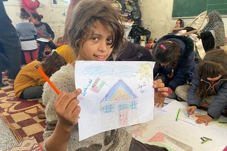 Ein Mädchen aus Gaza hält ihr gemaltes Bild in die Kamera